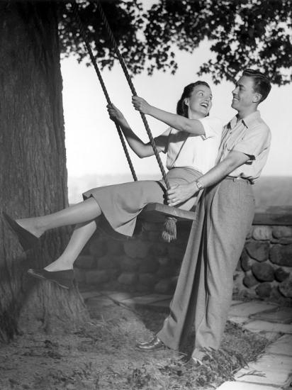 Man Pushing Woman On Swing Hanging From Man Pushing Woman On Swing Hanging From
